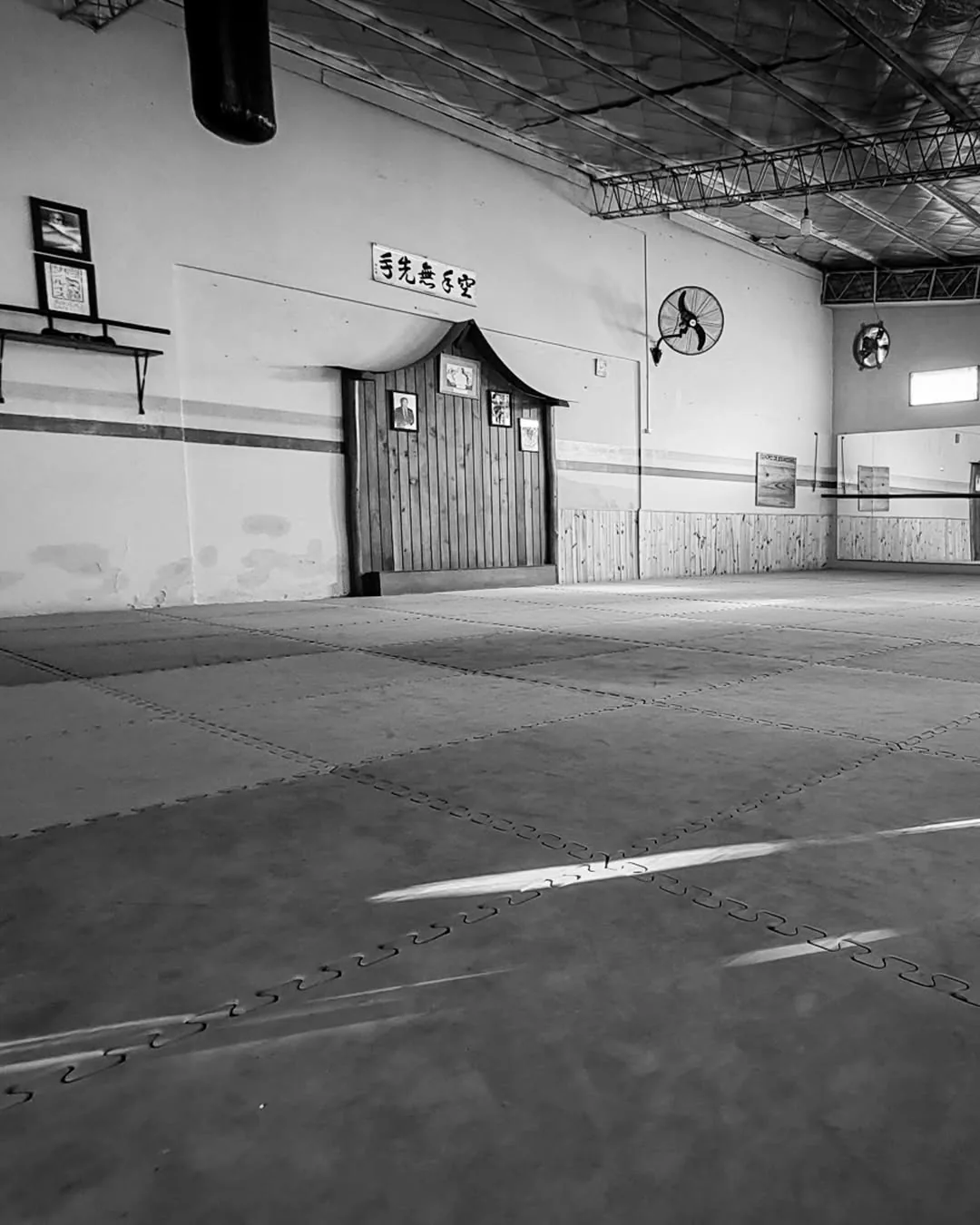 Vista en blanco y negro del espacio de entrenamiento del dojo.