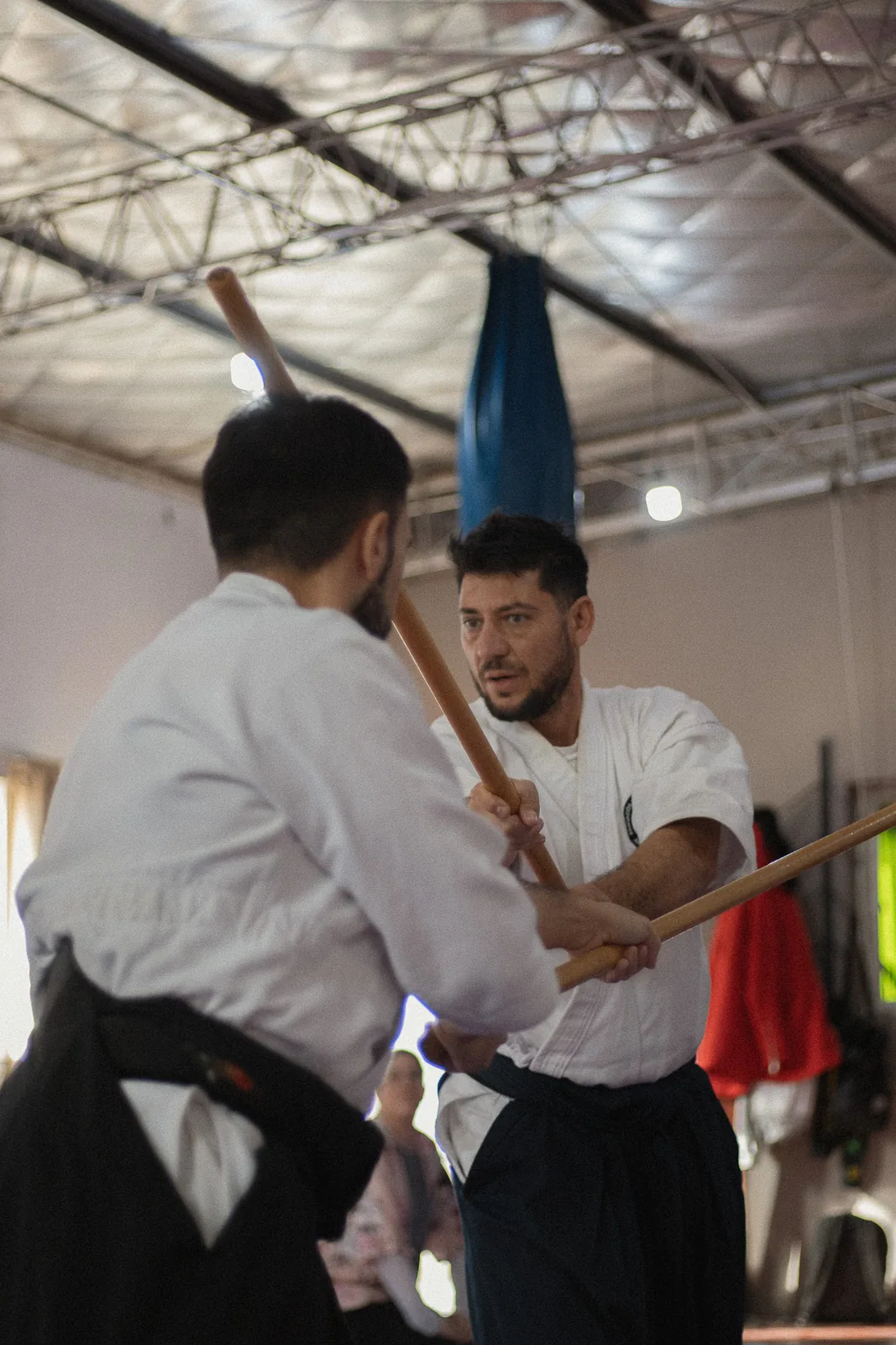 Dos practicantes entrenan con jō en el dojo de Aikidō.